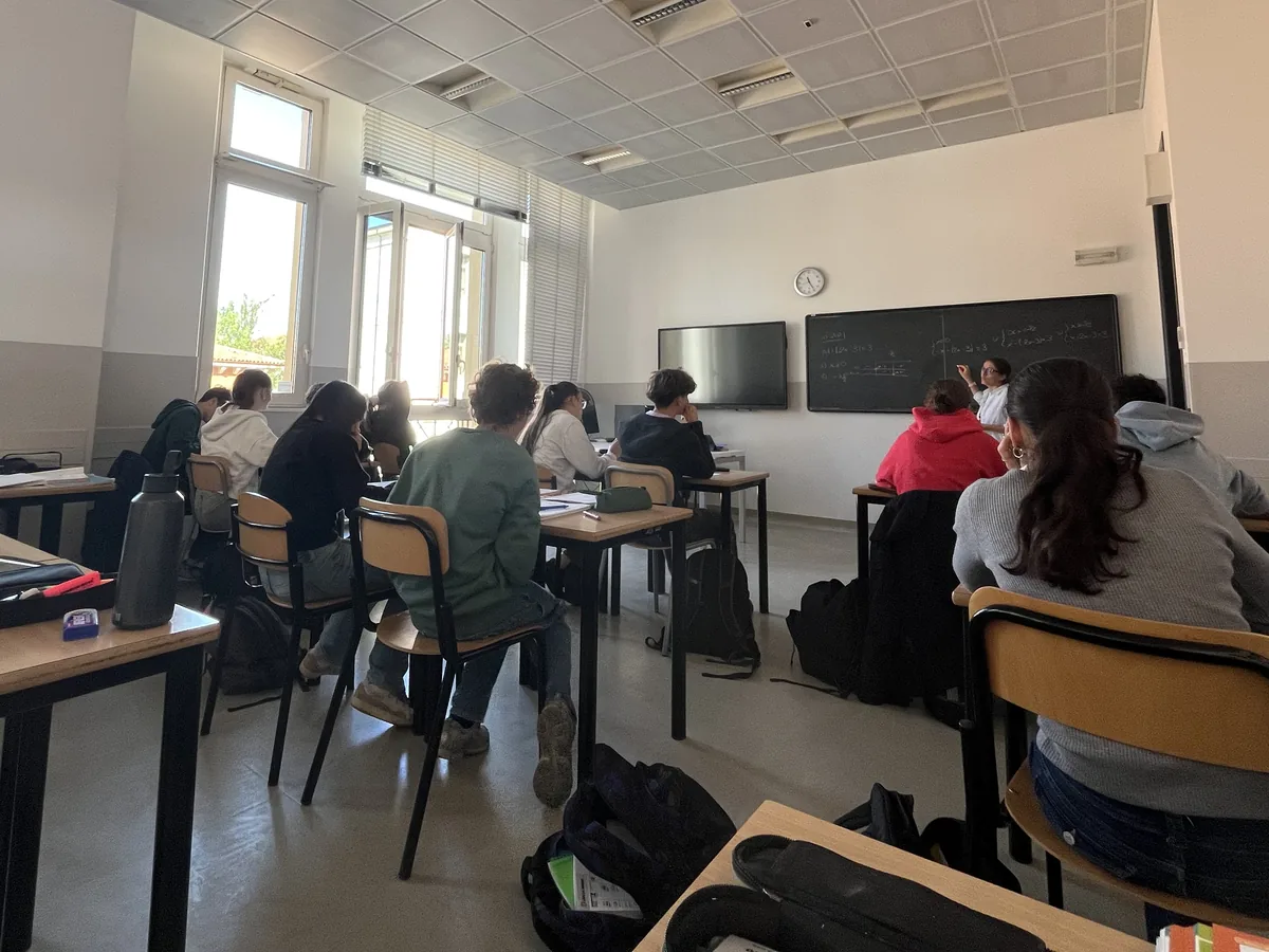 Una lezione in un'aula luminosa: gli studenti seguono la docente alla lavagna
