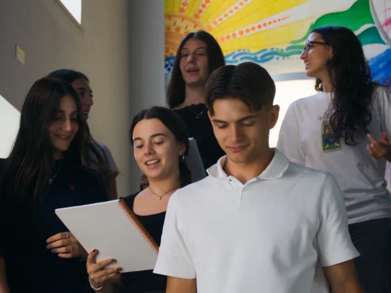 Un gruppo di studenti sorridenti davanti a un murale colorato